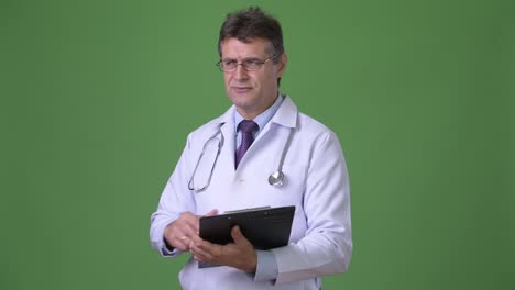 Mature-handsome-man-doctor-against-green-background