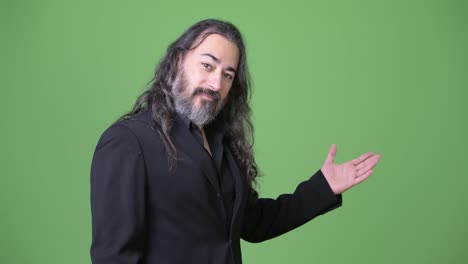 Studio-shot-of-mature-handsome-bearded-multi-ethnic-businessman-with-long-hair