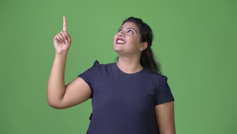 Young-overweight-beautiful-Indian-businesswoman-against-green-background