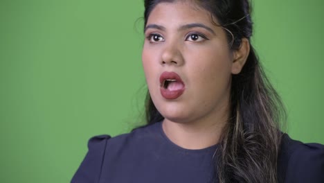 Young-overweight-beautiful-Indian-businesswoman-against-green-background