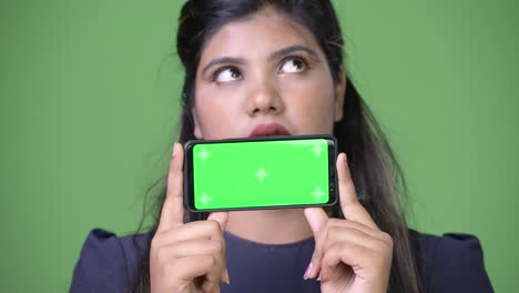 Young-overweight-beautiful-Indian-businesswoman-against-green-background