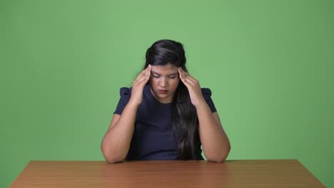 Young-overweight-beautiful-Indian-businesswoman-against-green-background