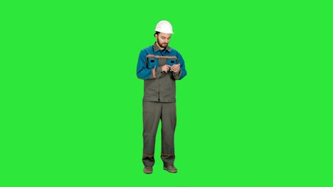 Trabajador-de-la-construcción-mediante-teléfono-celular-para-enviar-el-mensaje-en-una-pantalla-verde,-Croma-Clave