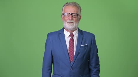 Handsome-senior-bearded-businessman-against-green-background