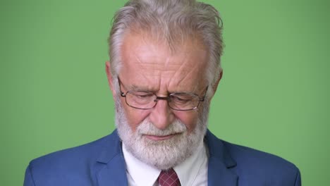 Handsome-senior-bearded-businessman-against-green-background