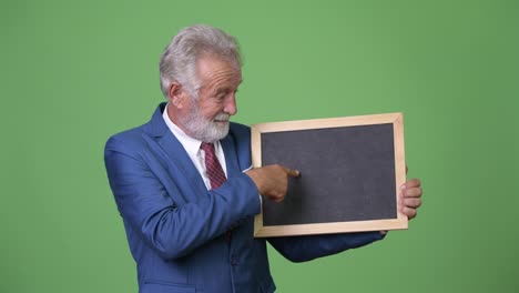 Handsome-senior-bearded-businessman-against-green-background