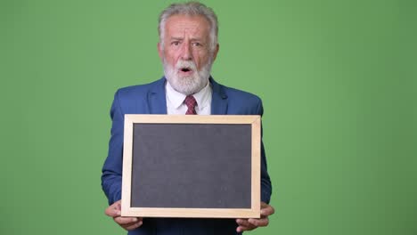 Handsome-senior-bearded-businessman-against-green-background