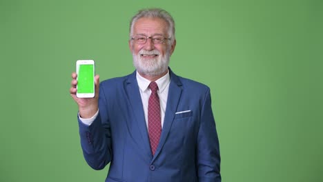 Handsome-senior-bearded-businessman-against-green-background