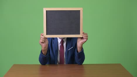 Handsome-senior-bearded-businessman-against-green-background