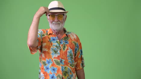 Handsome-senior-bearded-tourist-man-ready-for-vacation-against-green-background