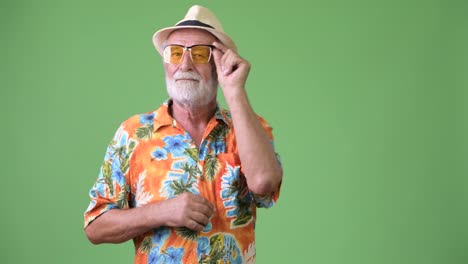 Handsome-senior-bearded-tourist-man-ready-for-vacation-against-green-background