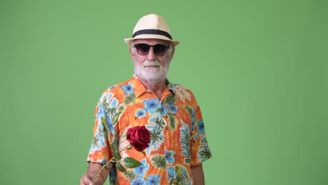 Handsome-senior-bearded-tourist-man-ready-for-vacation-against-green-background