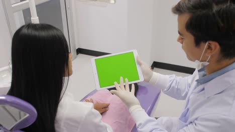 Dentist-explaining-procedure-to-patient-from-greenscreen-tablet