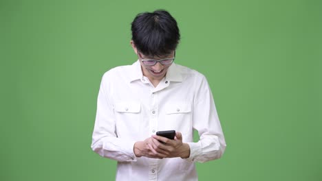 Happy-young-Asian-businessman-smiling-while-using-phone