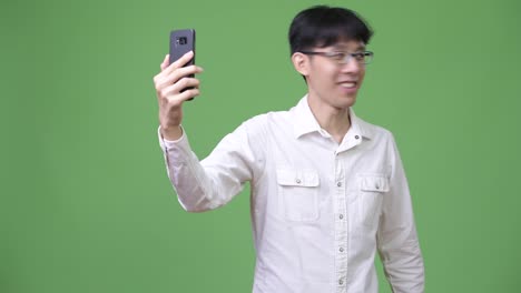 Happy-young-Asian-businessman-smiling-while-doing-video-call