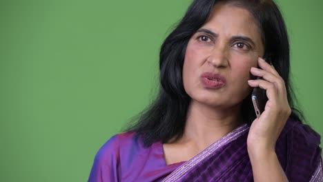 Close-up-shot-of-mature-beautiful-Indian-woman-talking-on-the-phone-while-thinking