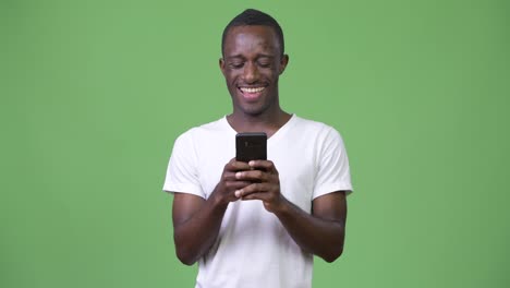 Young-African-man-using-phone-against-green-background