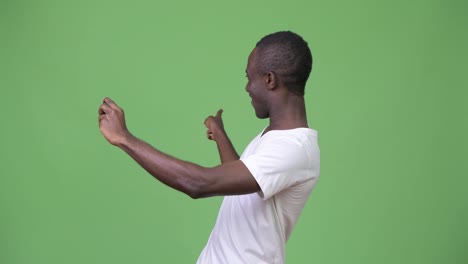 Young-African-man-video-calling-with-phone-against-green-background