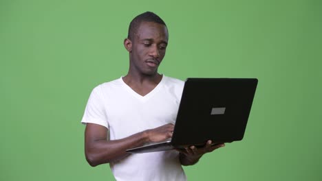 Young-happy-African-man-smiling-while-using-laptop