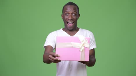 Young-happy-African-man-looking-surprised-while-opening-gift-box