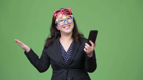 Mature-beautiful-Asian-businesswoman-using-phone-while-wearing-many-eyeglasses-as-funny-concept