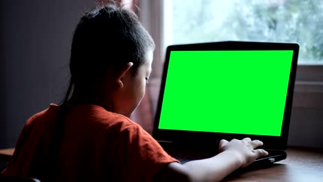 Asia-muchacho-de-7-años-de-edad-utilizar-laptop-búsqueda-información-en-Internet-en-el-hogar-con-pantalla-verde.-Concepto-de-la-tecnología-en-la-vida-cotidiana.