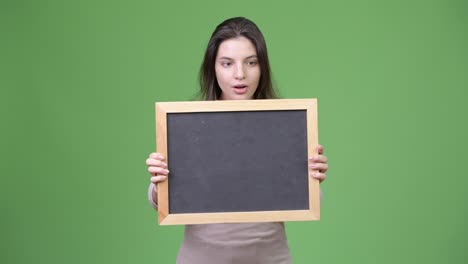 Young-beautiful-woman-looking-shocked-while-holding-blackboard