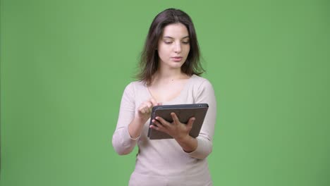 Young-happy-beautiful-woman-thinking-while-using-digital-tablet