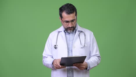 Handsome-Persian-bearded-man-doctor-reading-clipboard