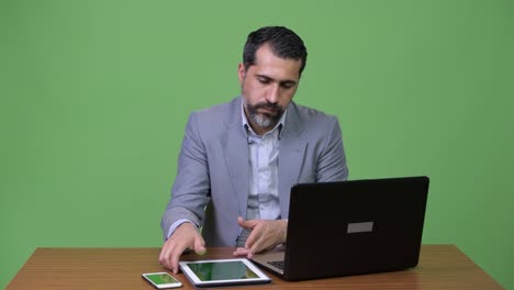 Stressed-Persian-bearded-businessman-multi-tasking-at-work-and-looking-busy