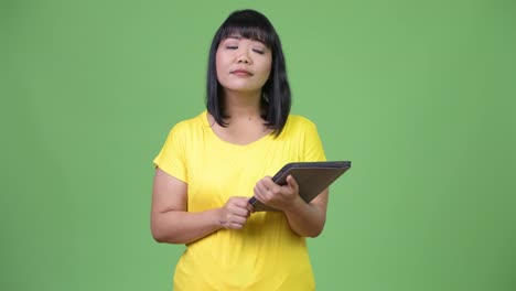 Schöne-asiatische-Frau-denken-bei-der-Verwendung-von-digital-Tablette