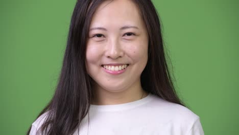 Young-happy-Asian-woman-smiling-against-green-background