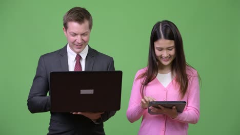 Junge-asiatische-Frau-und-junger-Geschäftsmann-mit-Laptop-und-digital-Tablette-zusammen