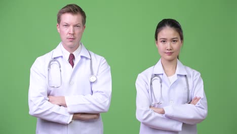 Multi-ethnic-couple-doctors-with-arms-crossed-together