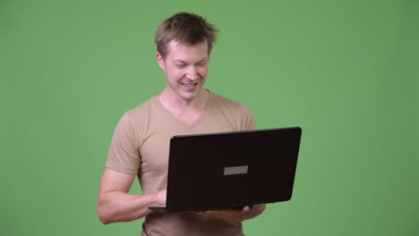 Young-happy-Scandinavian-man-thinking-while-using-laptop