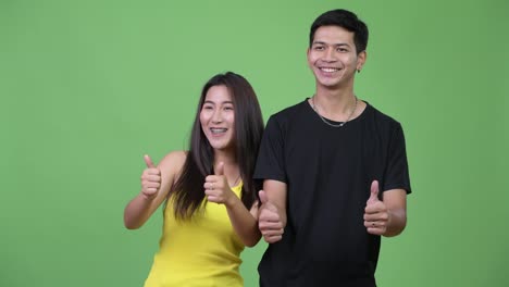 Young-Asian-couple-giving-thumbs-up-together