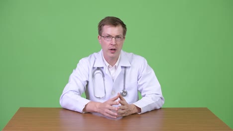 Young-Confident-Man-Doctor-Sitting-And-Talking-While-Gesturing