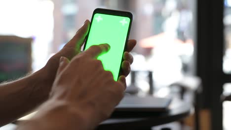 Nahaufnahme-der-Hand-des-Mannes-über-Mobiltelefon-mit-Greenscreen-im-Restaurant