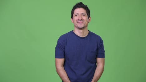 Happy-Hispanic-man-thinking-against-green-background