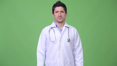 Hispanic-Mann-Arzt-vor-grünem-Hintergrund