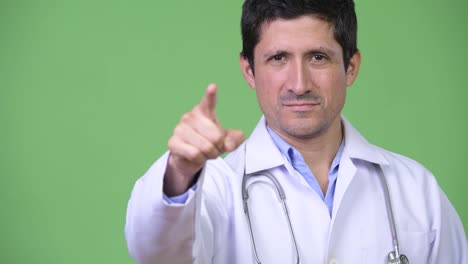 Feliz-médico-de-hombre-hispano-apuntando-a-cámara