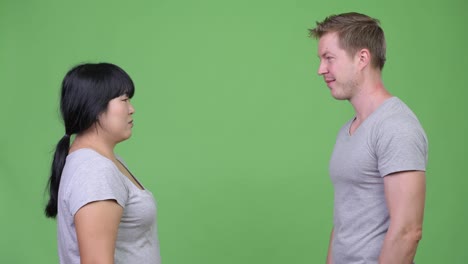 Young-multi-ethnic-couple-giving-high-five-and-crossing-arms-together