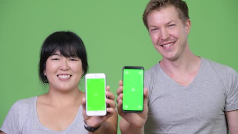 Young-happy-multi-ethnic-couple-showing-two-phones-together