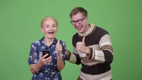 Happy-grandmother-and-grandson-using-phone-then-giving-thumbs-up-together