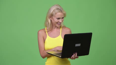 Junge-glücklich-schöne-blonde-Frau-mit-Laptop-vor-grünem-Hintergrund