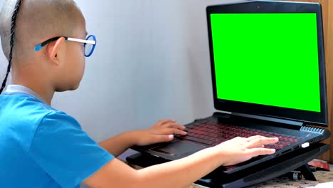 Little-Asians-boy-playing-laptop-computer-and-green-screen.-Happy-enjoy-kids-playing-computer-at-home.