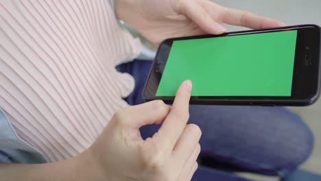 Cheerful-happy-asian-young-woman-sitting-in-cafe-using-smartphone-device-with-green-screen-for-talking,-reading-and-texting.-Women-lifestyle-concept.