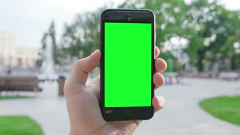 A-Hand-Holding-a-Phone-with-a-Green-Screen