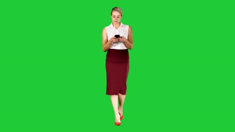 Woman-typing-write-message-on-smart-phone-and-walking-on-a-Green-Screen,-Chroma-Key