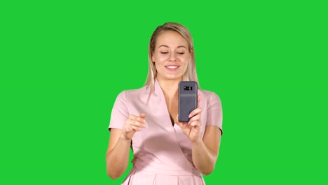 Beautiful-blond-head-lady-making-video-call-using-cell-phone-on-a-Green-Screen,-Chroma-Key